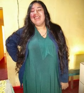 Ariane teve melhoras significativas após incluir CBD no tratamento para epilepsia. Foto de Ariane sorrindo com a mão direita nos quadris.