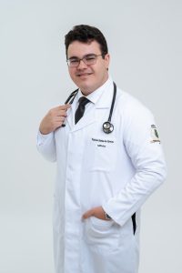 Foto do recém-formado Vinícius com jaleco e estetoscópio pendurado no pescoço