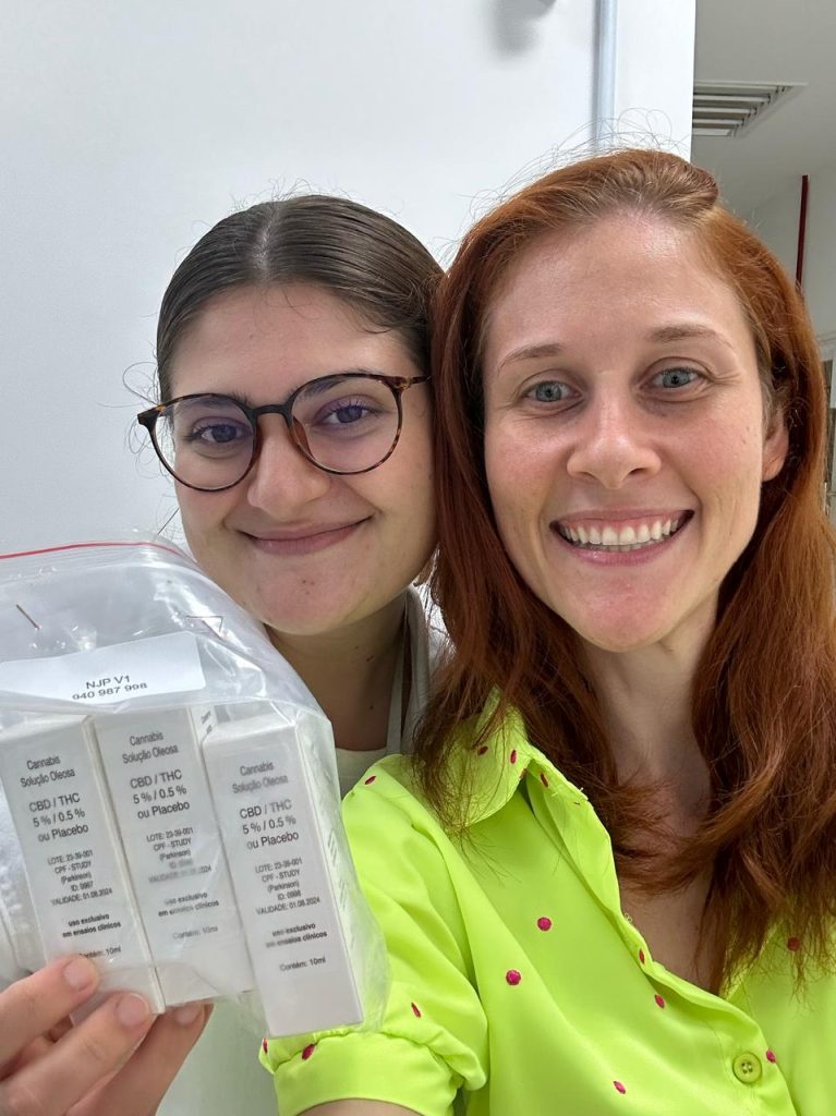 Ana e outra mulher exibem embalagem contendo medicamentos usados no estudo