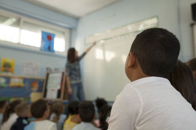 elementary school children listening to the teacher's explanation in a school class
