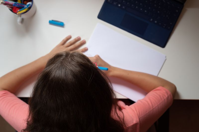 An overhead shot of a child doing homework at home with a tablet